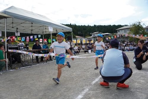 運動会で年長児がとても楽しそうに走り切る。